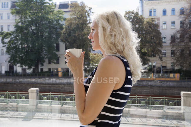 Side view of mature woman outdoors holding coffee cup looking away — Stock Photo