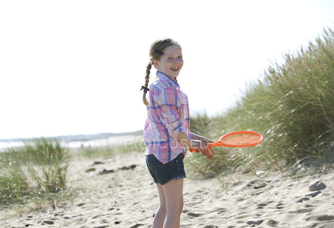 Seitenansicht eines Mädchens mit orangefarbenem Sportschläger, das lächelnd in die Kamera blickt — Stockfoto
