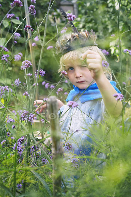 Мальчик наряжается и играет с растениями в саду — стоковое фото
