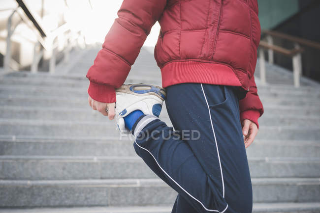 Обрезанный снимок молодого бегуна на городской лестнице разогревается — стоковое фото