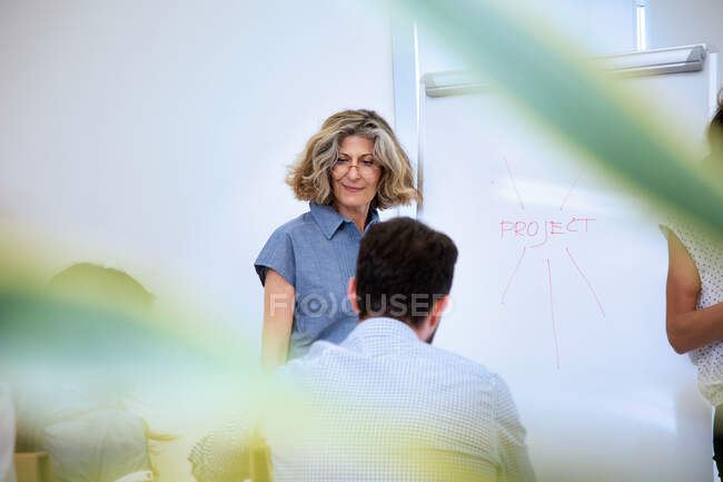 Старшая женщина представляет бизнес-команде в офисе — стоковое фото