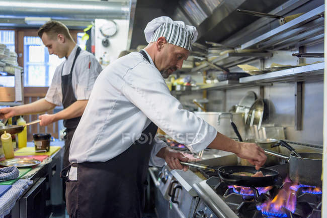 Chefs preparing food in traditional Italian restaurant kitchen — Stock Photo