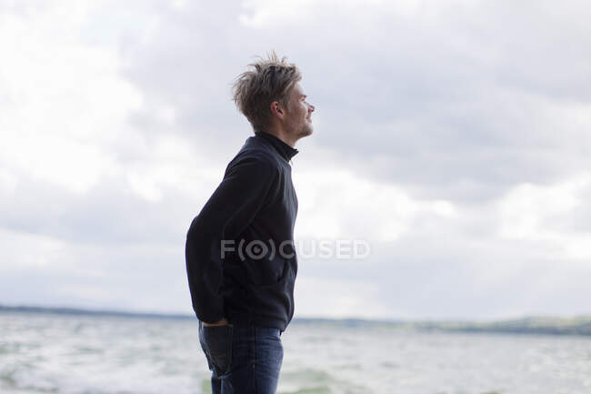 Hombre mirando desde la orilla del lago, Lago Starnberg, Baviera, Alemania - foto de stock