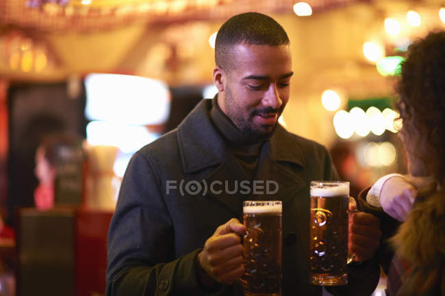 Mid adulto homem entregando jovem mulher copo de cerveja, olhando para baixo sorrindo — Fotografia de Stock