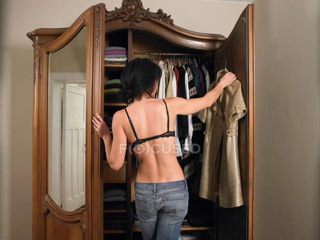 Woman in bra, choosing her outfit — Stock Photo