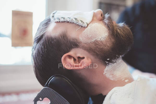 Male clients face with shaving cream and eyes covered in barber shop — Stock Photo