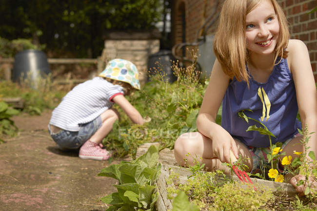 Two sisters digging in garden grass and soil — Stock Photo