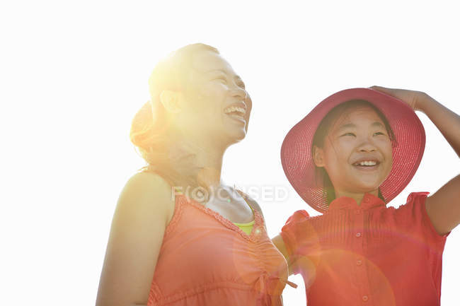 Retrato de mujer e hija sonrientes a la luz del sol - foto de stock