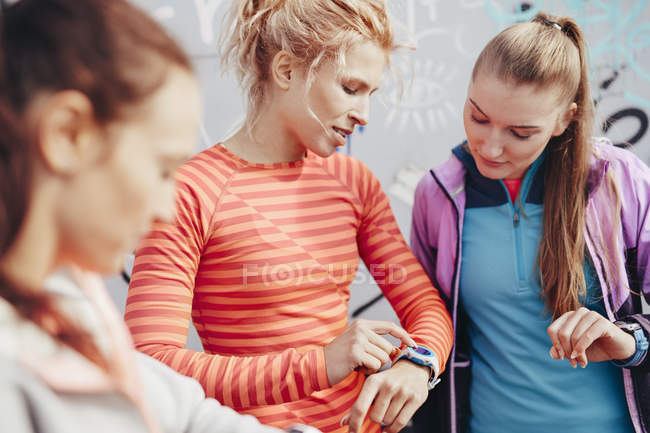 Three female runners checking time on smartwatch — Stock Photo