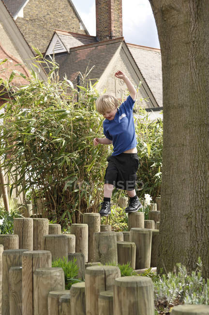 School boy stepping on log fence — Stock Photo