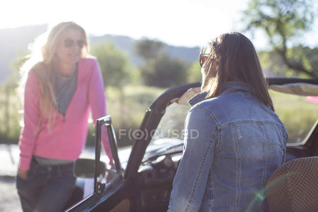Две зрелые женщины разговаривают, рядом с кабриолетом — стоковое фото