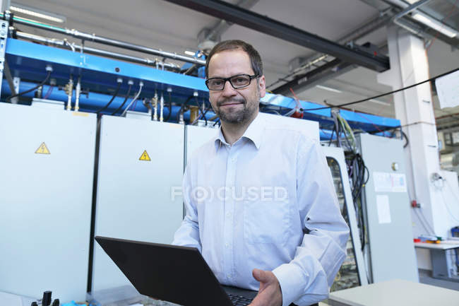 Portrait of manager holding laptop in workshop — Stock Photo
