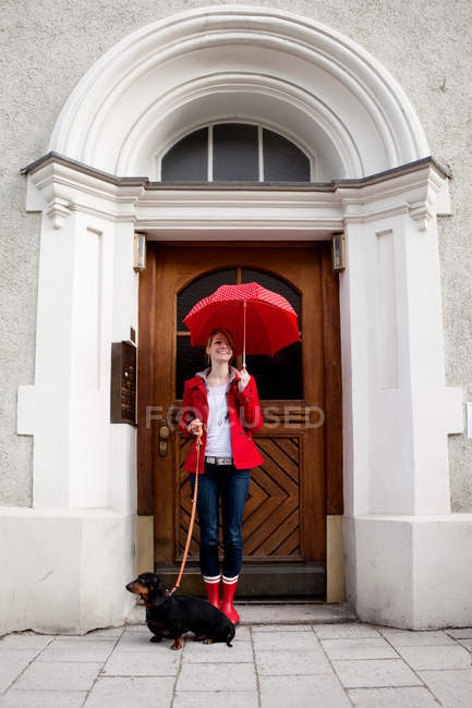 Mujer con paraguas y salchicha perro - foto de stock