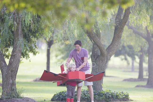 Padre preparando avión de juguete para hijo en parque - foto de stock