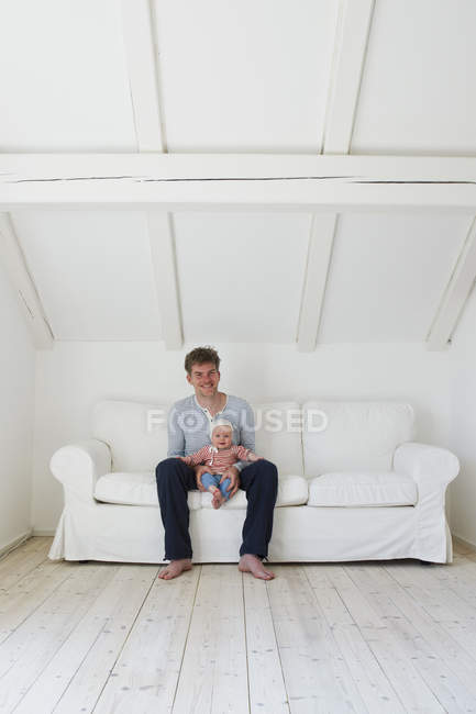 Portrait of mature father with baby daughter on sofa — Stock Photo