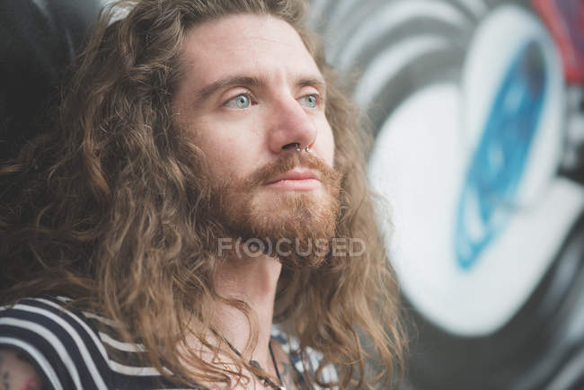 Retrato de jovem hippie masculino encostado à parede de grafite — Fotografia de Stock