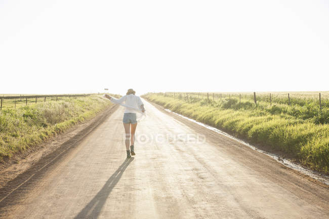 Взрослая женщина идет по проселочной дороге, вид сзади — стоковое фото