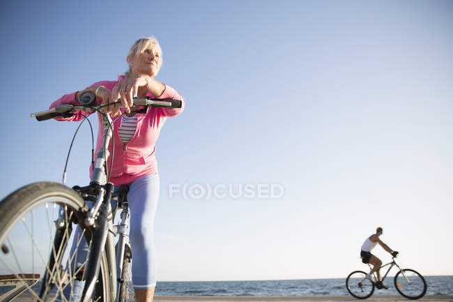 Seniorin mit Fahrrad am Strand — Stockfoto