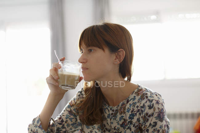 Mitte erwachsene Frau trinkt Kaffee in Küche — Stockfoto