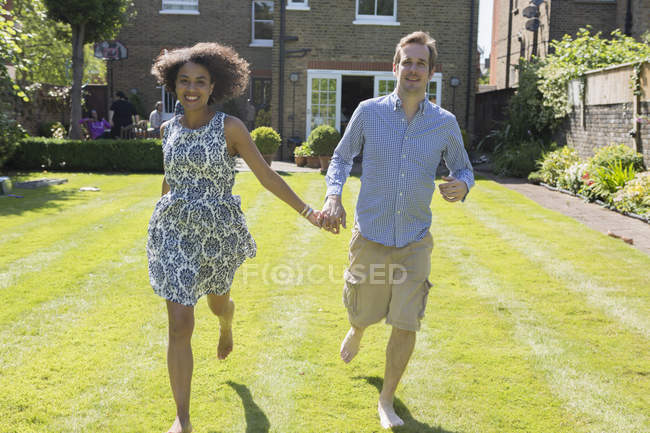Середня доросла пара біжить, рука в руці, в саду — стокове фото