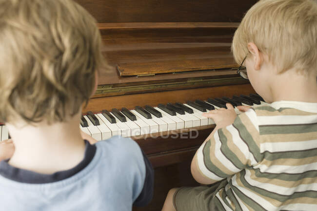Мальчики играют на фортепиано вместе — стоковое фото