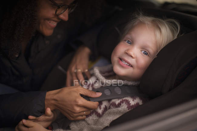 Madre ajustando el cinturón de seguridad del hijo en el coche - foto de stock