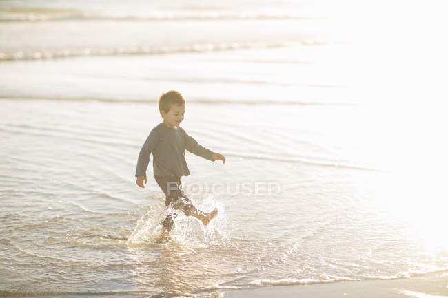Niño remando y chapoteando en el mar - foto de stock