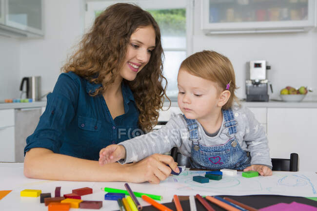 Teenagerin und Kleinkind zeichnen am Küchentisch — Stockfoto