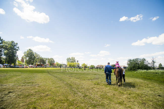 Rear view of young man and two girls riding horse in field, Rezh, Sverdlovsk Oblast, Russia — Stock Photo
