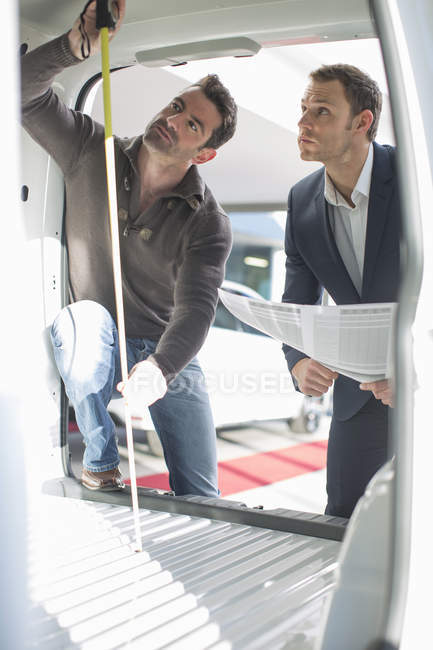 Cliente y vendedor revisando la altura interior del vehículo en el concesionario de automóviles - foto de stock