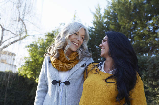 Women in garden arms around each other face to face smiling — Stock Photo