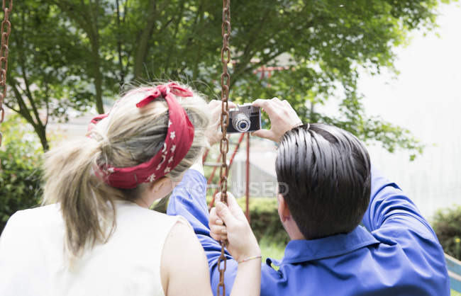 Visão traseira do jovem casal vintage levando selfie com câmera no jardim — Fotografia de Stock