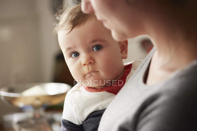 Mère portant bébé garçon dans la cuisine — Photo de stock