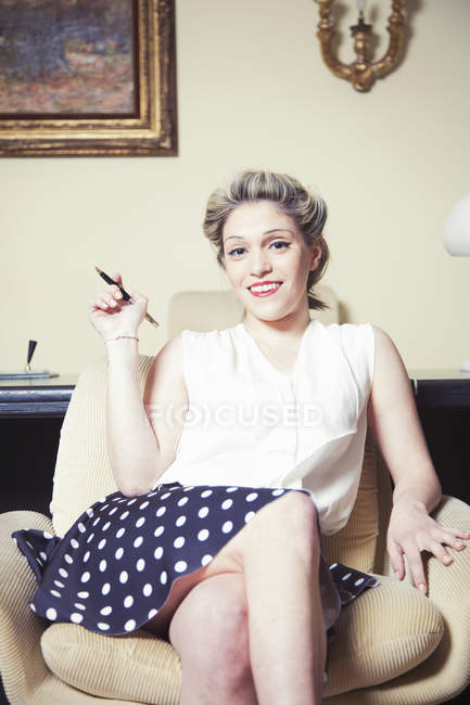 Portrait of young woman in armchair wearing vintage clothes — Stock Photo