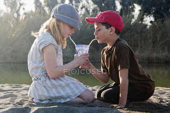 Ragazzo e ragazza che condividono un drink al fiume — Foto stock