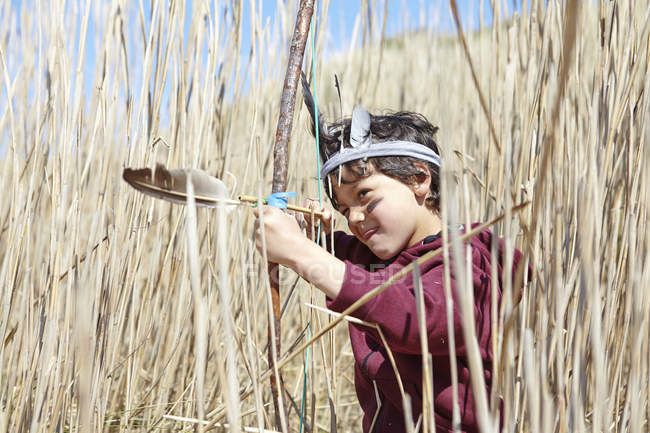 Giovane ragazzo che indossa un vestito di fantasia, tenendo arco e freccia fatti in casa — Foto stock