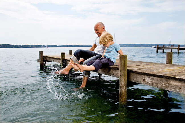 Boy splashing with grandfather at lake — Stock Photo