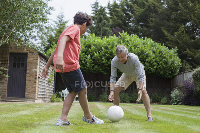 Дідусь і онук грають у футбол в саду. — стокове фото