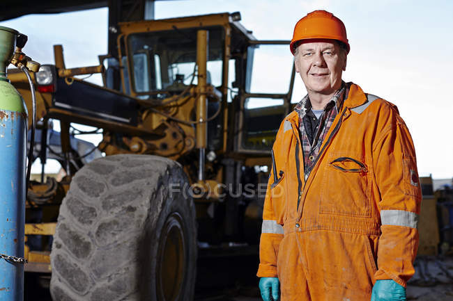 Porträt eines Steinbrucharbeiters neben einem Bagger auf dem Steinbruchgelände — Stockfoto
