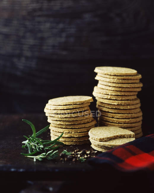 Stack of black pepper and rosemary oatcakes on dark background — Stock Photo