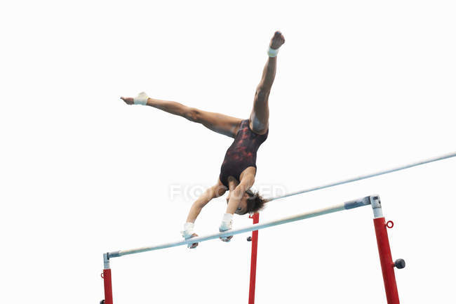 Joven gimnasta actuando en barras irregulares - foto de stock