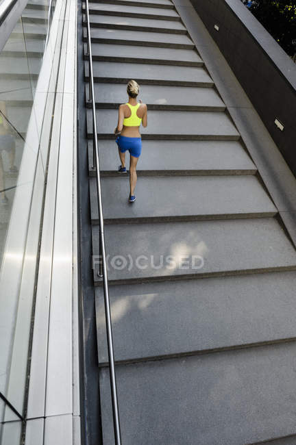 Female jogger running up steps in city — Stock Photo
