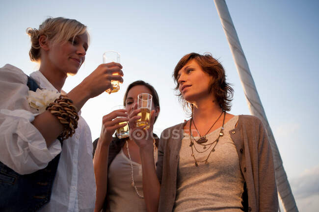 Girls drinking beer on boat — Stock Photo