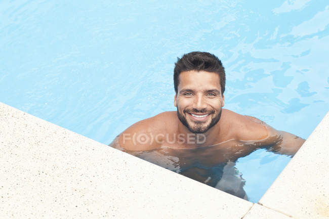 Homem em pé na piscina e olhando para a câmera — Fotografia de Stock