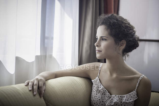 Jeune femme regardant par la fenêtre — Photo de stock