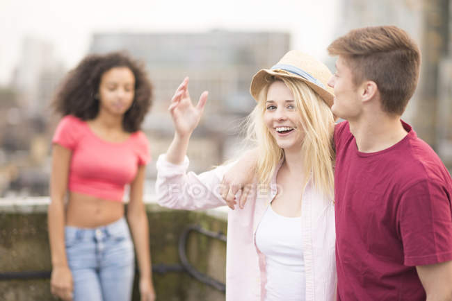 Young couple walking in city, woman wearing hat, young woman in background — Stock Photo