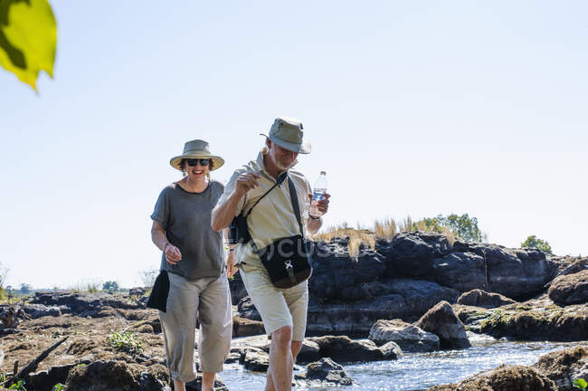 Hombre y mujer mayores explorando las rocas del río, cerca de Victoria Falls, Zambia - foto de stock