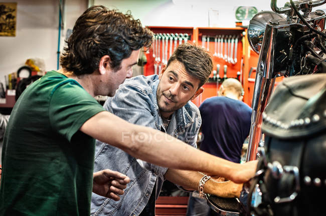 Mecânica masculina conversando na oficina de motocicleta — Fotografia de Stock