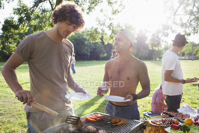 Giovani uomini grigliate al tramonto festa parco — Foto stock