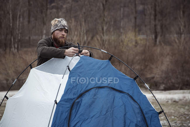 Mid adult man putting up tent — Stock Photo
